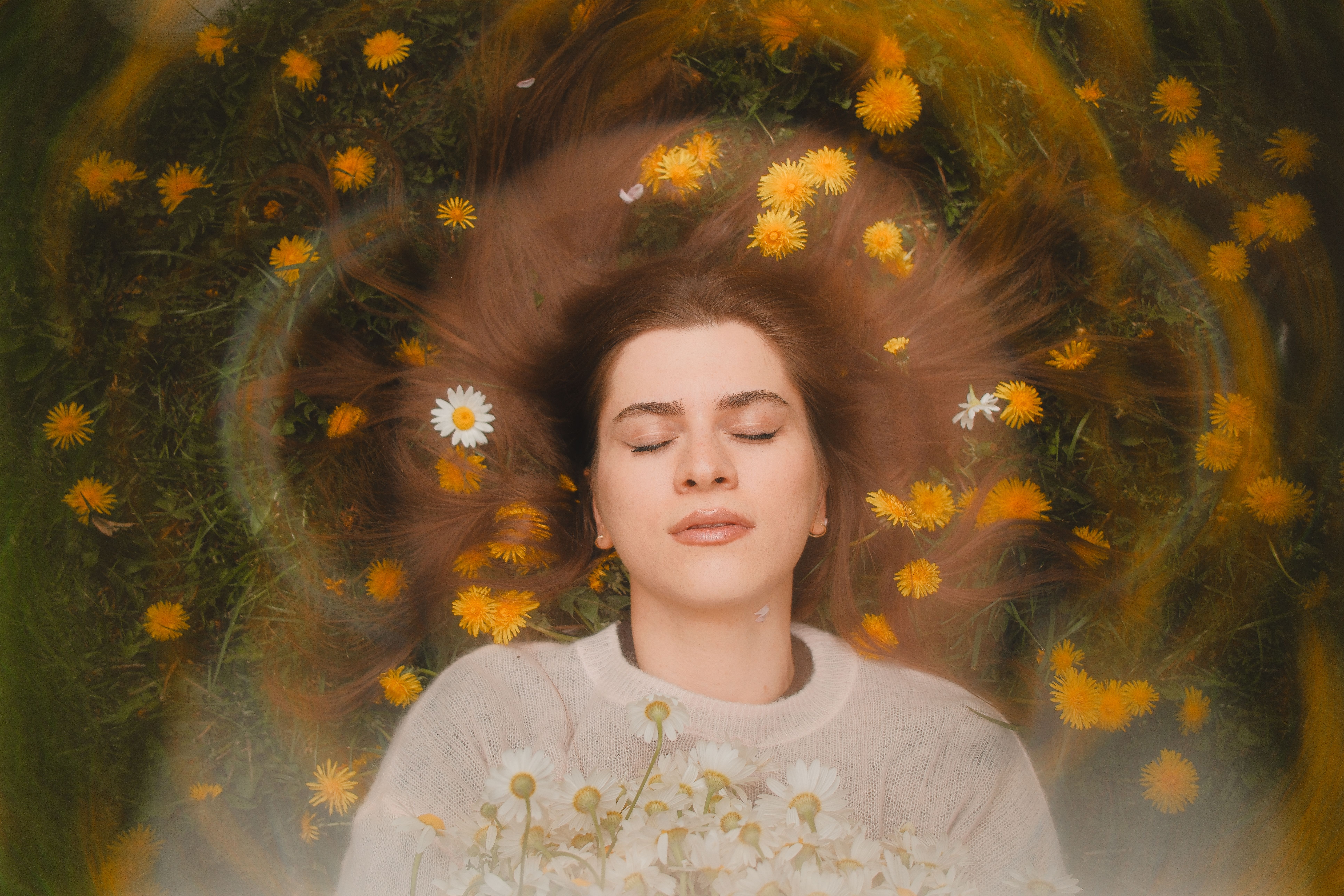 Vrouw met gesloten ogen tussen bloemen tijdens een oefening om in contact te komen met haar intuïtie